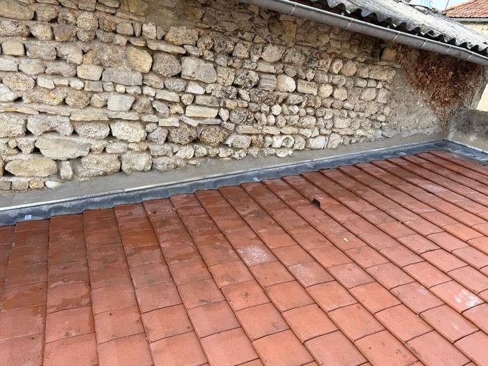 Toiture en tuiles rénovée le long d’un mur en pierre